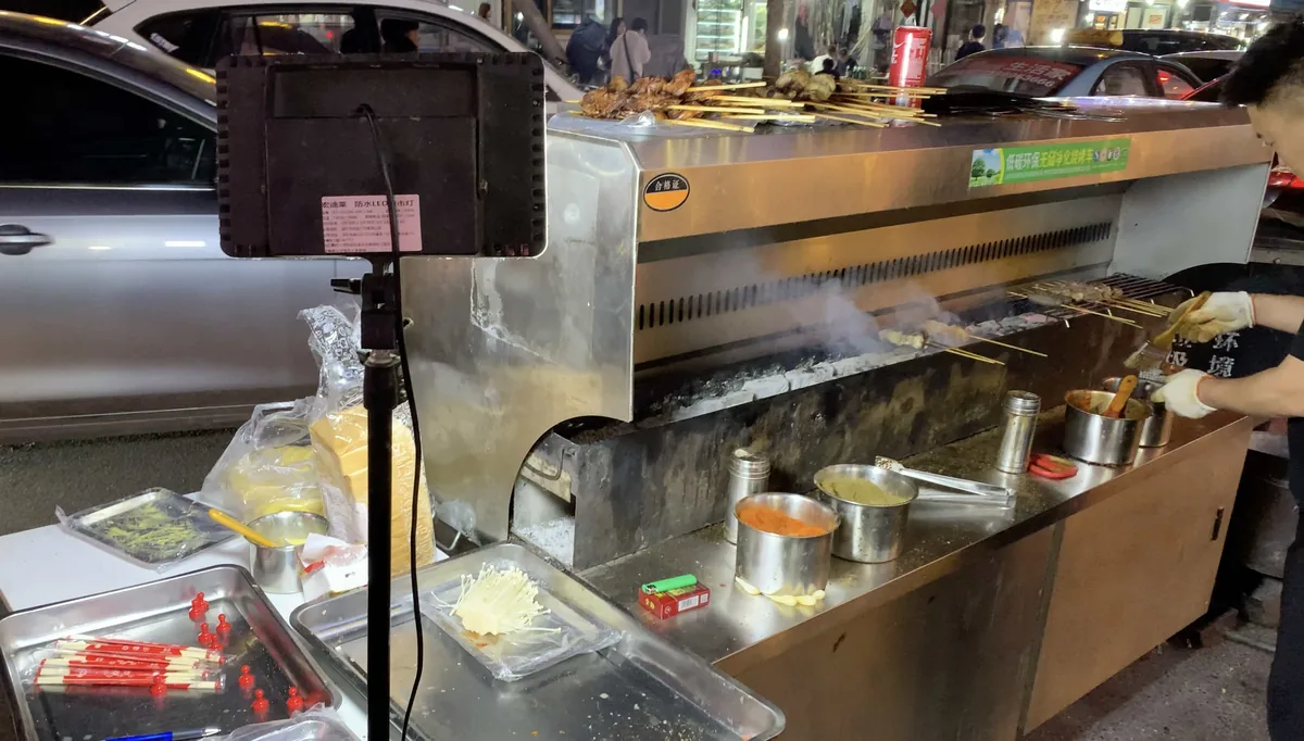 BBQ grill with seafood skewers cooking and a large exhaust fan