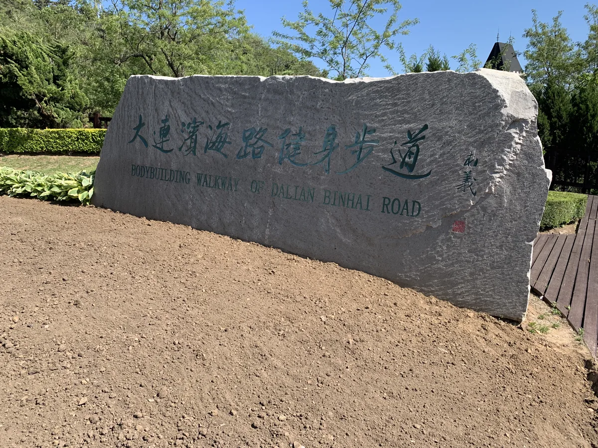 Stone marker reading Dalian Binhai Road Bodybuilding Walkway in Chinese and English