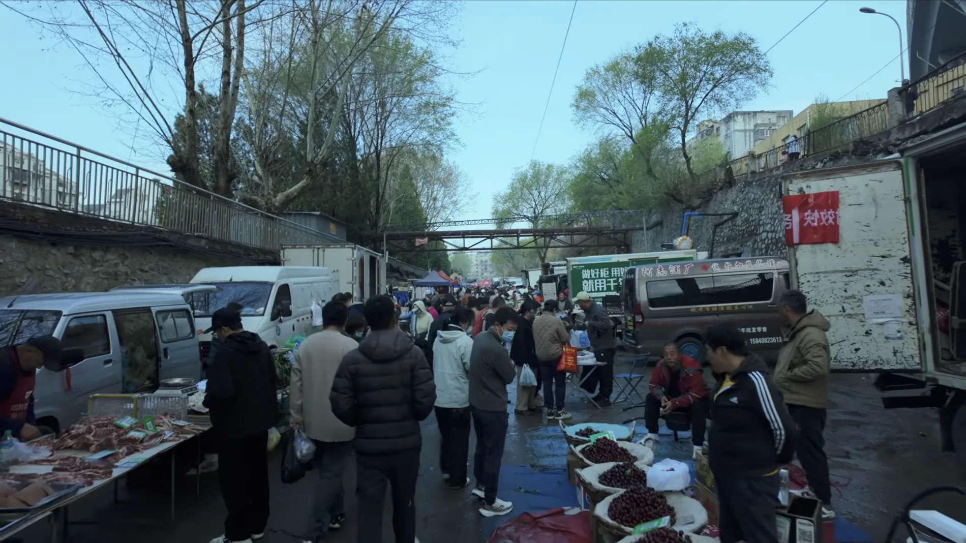 Busy local morning market street in Dalian with vendors, trucks and shoppers