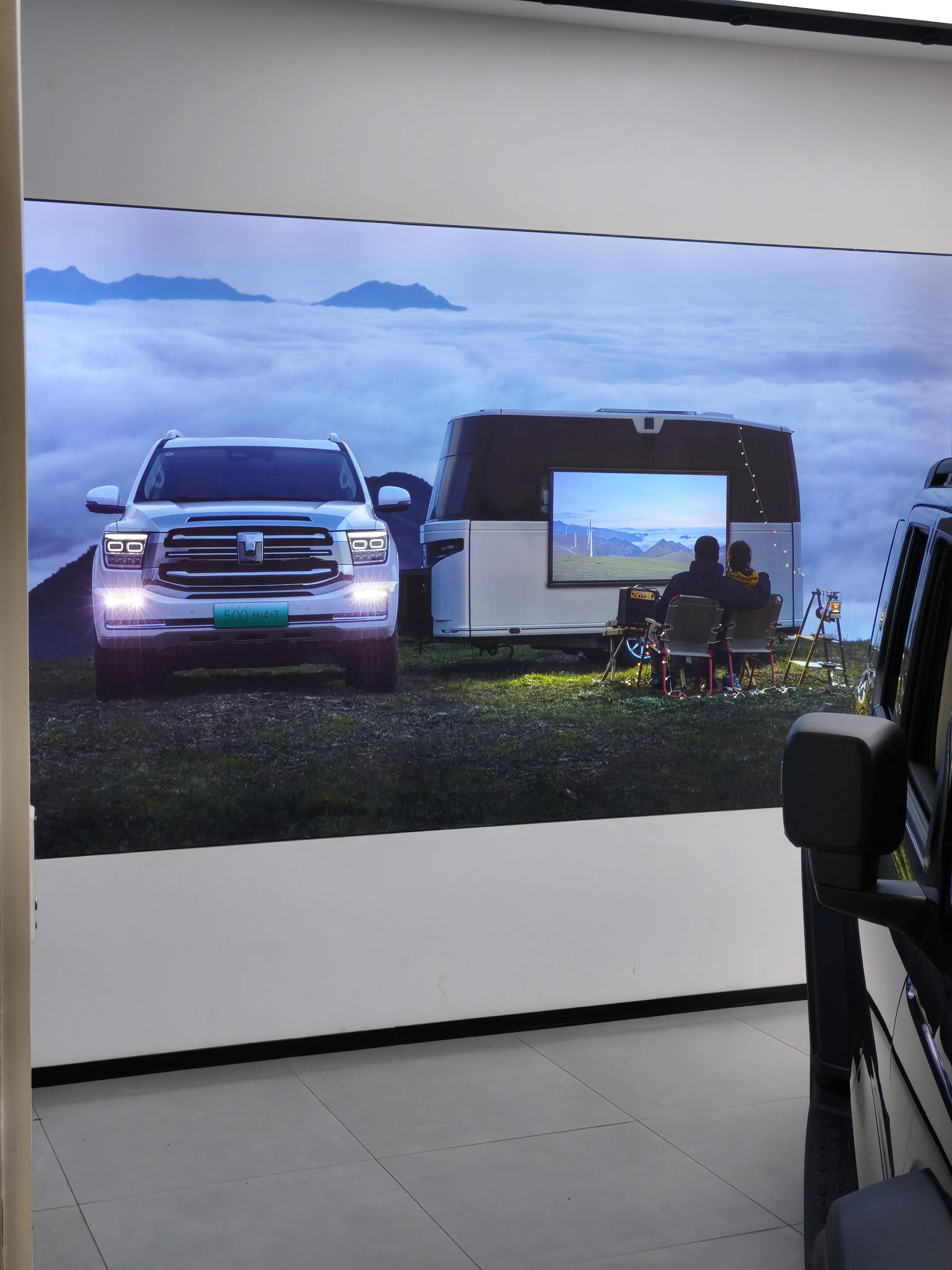 Large promotional display showing SUV towing a smart caravan with outdoor cinema