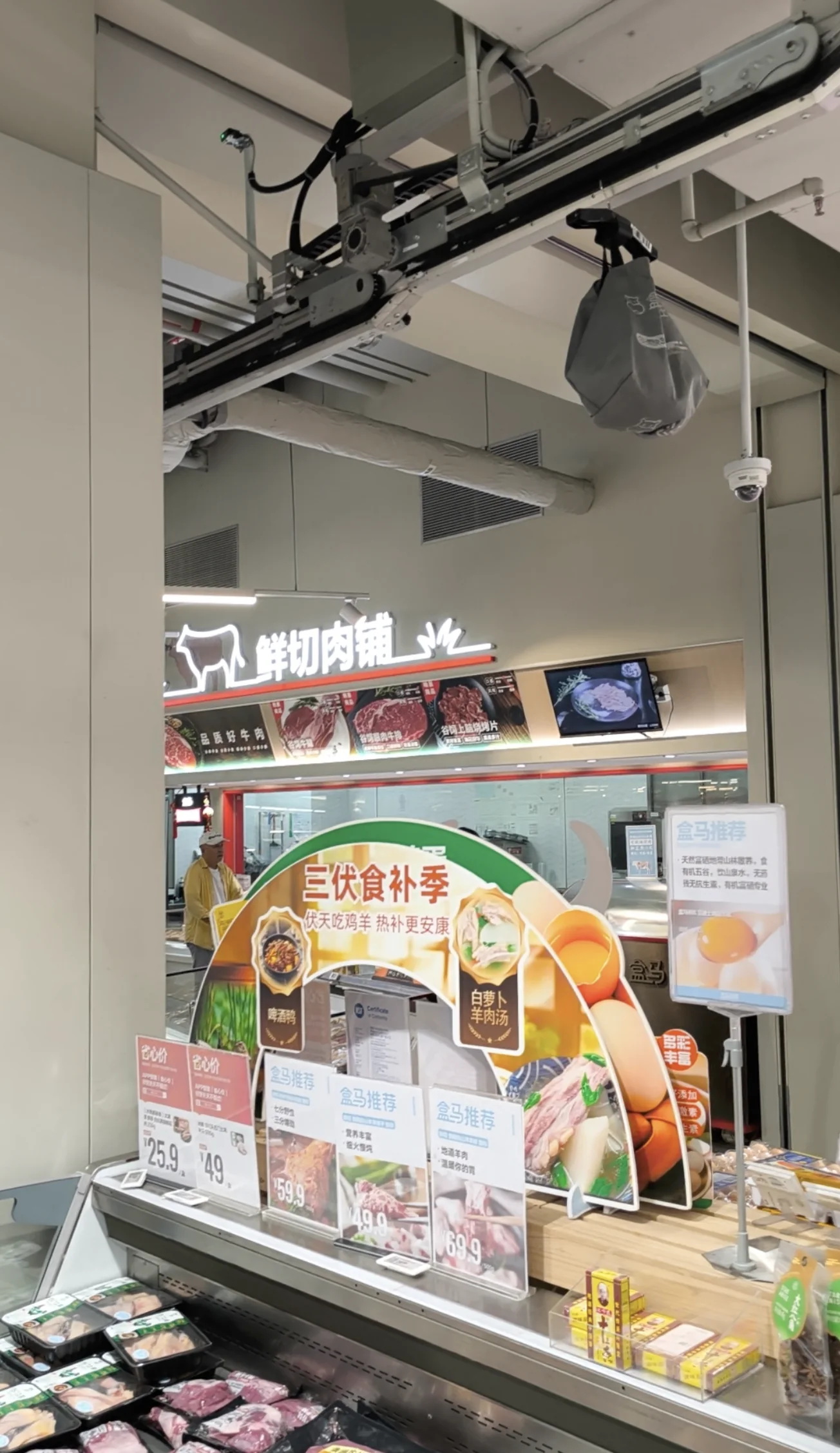 Insulated grey order bag hanging from an overhead conveyor rail in a Shanghai Freshippo supermarket