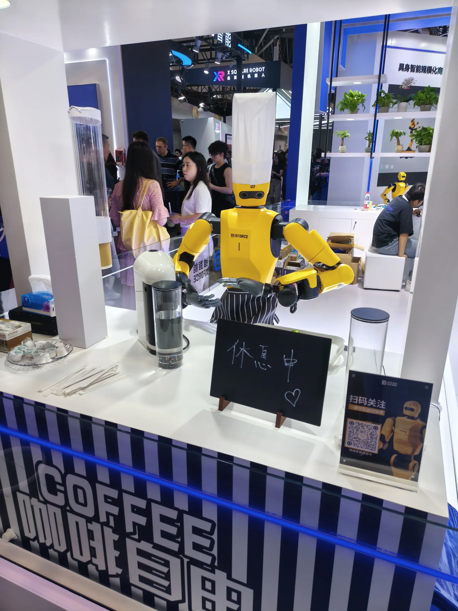 Yellow DexForce robot barista at WAIC 2025 with sign saying 'on break'